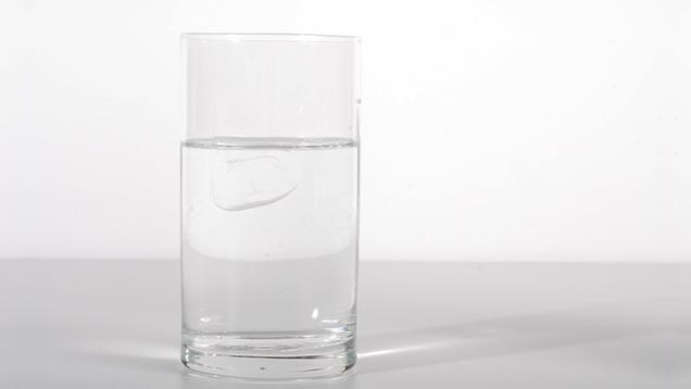 Schwimmender Eiswürfel im Wasserglas